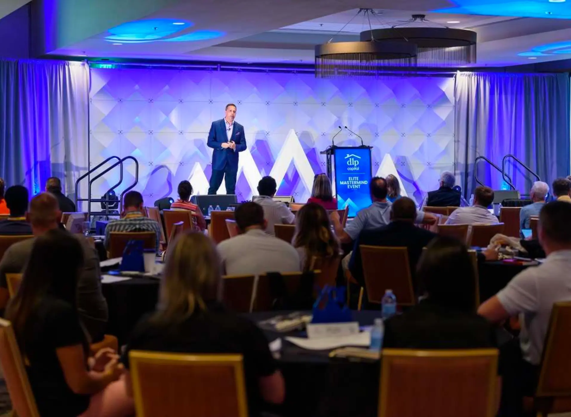 Aaron Bare speaking onstage at DLP Capital